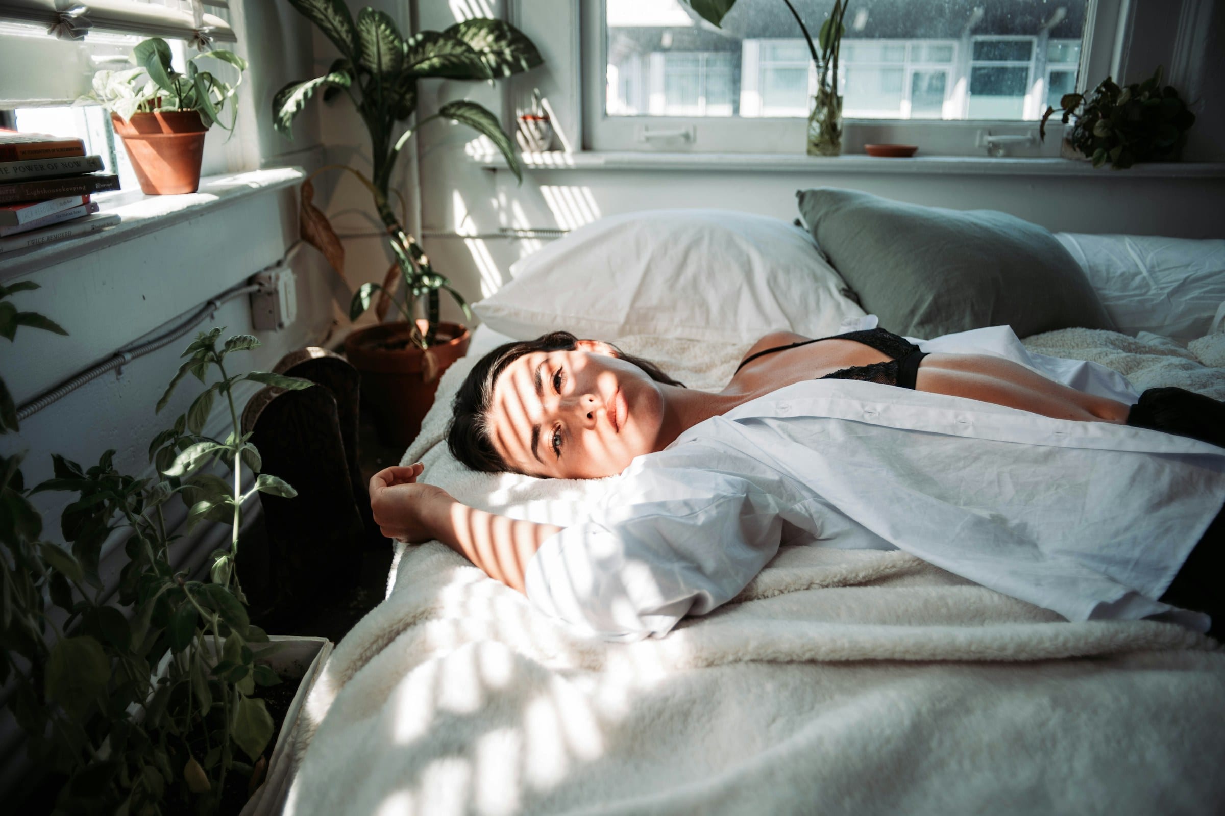 A woman rests peacefully in a sunlit bedroom, reflecting the restorative sleep that upper cervical care aims to support.