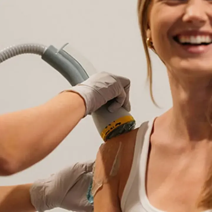 SoftWave OrthoGold applicator, identifiable by its gold band, being applied to a patient’s shoulder during regenerative shockwave therapy.
