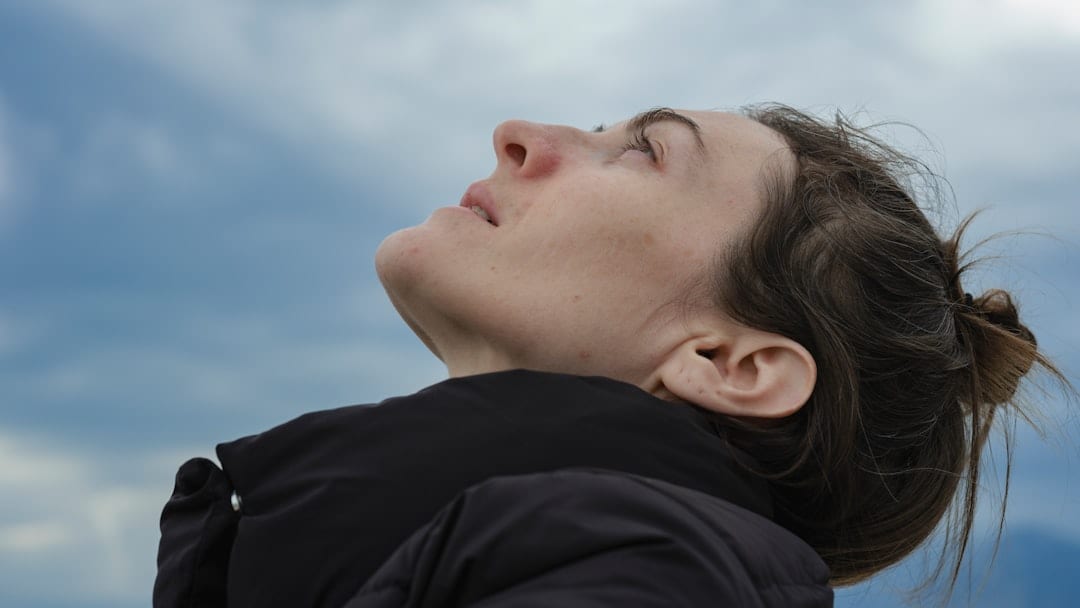 A woman tilts her head back with eyes closed, embodying calm, restored function, and renewed well-being through upper cervical care.