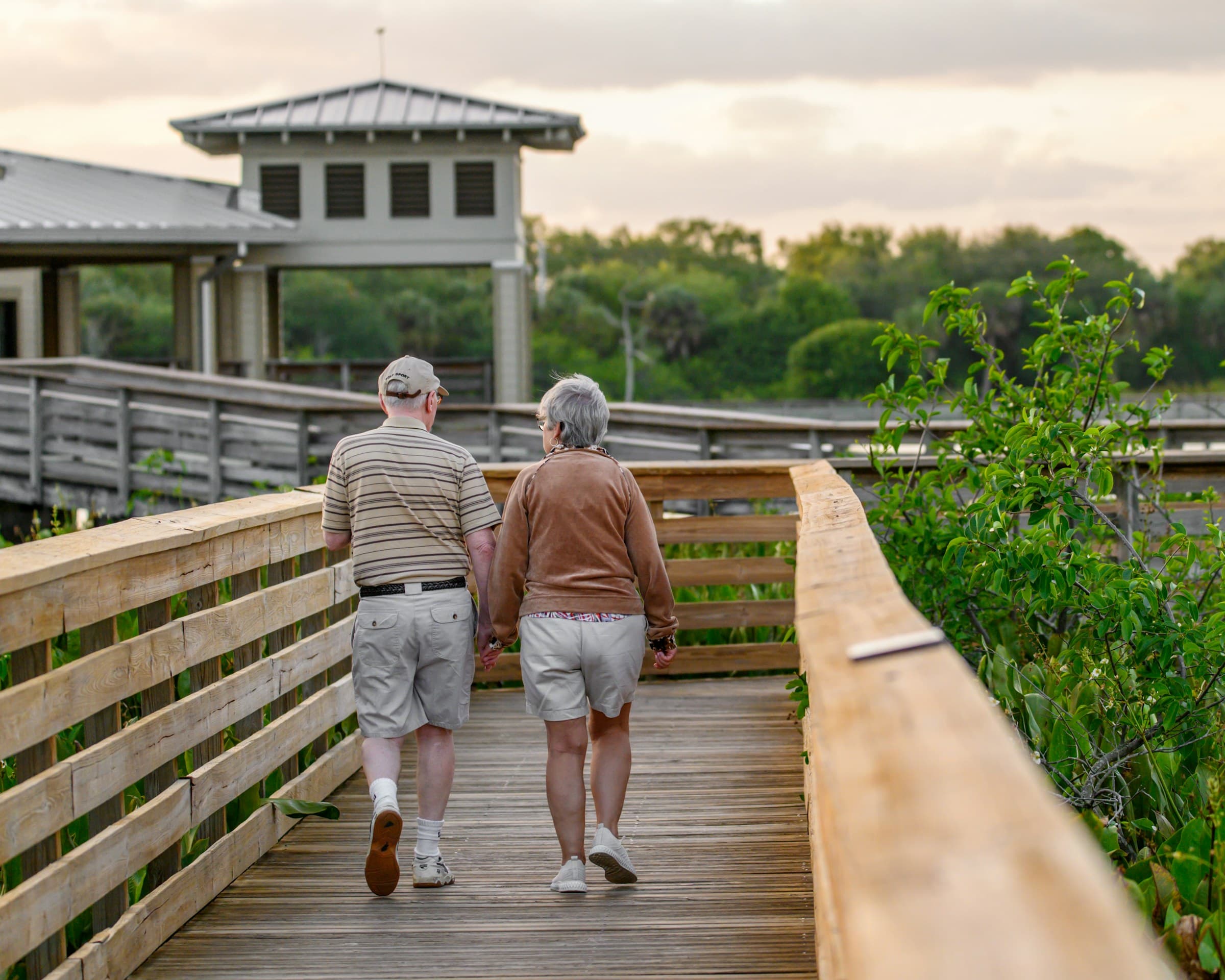 Senior couple walking comfortably along a boardwalk, reflecting the restored mobility and independence patients experience after addressing sciatic nerve pain without surgery.