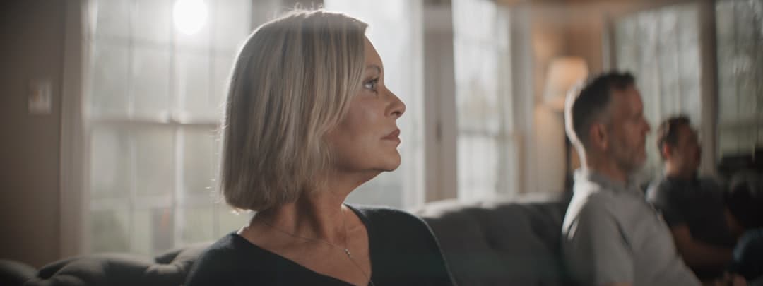 A woman in her fifties pauses in a quiet, warmly lit moment — reflecting the restored balance and well-being that upper cervical care can bring to women at every stage of life.