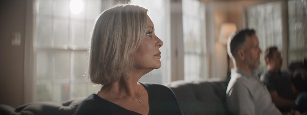 A woman in her fifties pauses in a quiet, warmly lit moment — reflecting the restored balance and well-being that upper cervical care can bring to women at every stage of life.