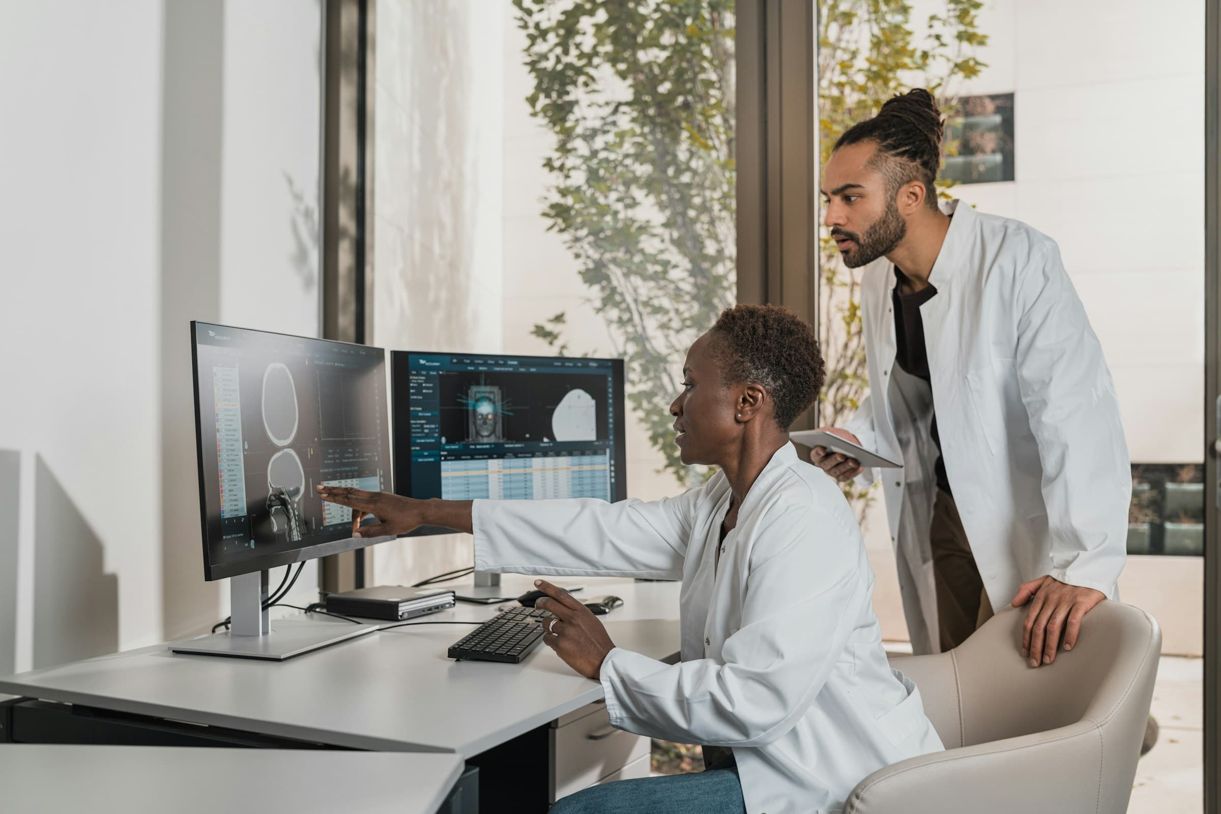 Two members of our clinical team reviewing advanced diagnostic scans of the head and neck on monitors in a bright, calm clinic.